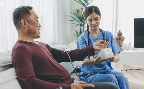 a nurse taking a blood pressure reading for an elderly man at home in a comfortable setting health monitoring and assessment for wellness
