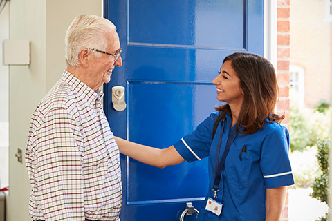 smiling elderly man greeting caregiver at door home care services 8 ways to enhance care