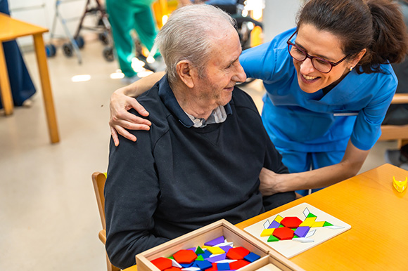 caregiver interacting with elderly man playing with colorful puzzle pieces encouraging social engagement and cognitive activity 3 benefits of interaction