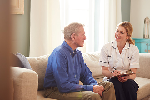 nurse talking to elderly male patient in living room home care 9 essential tips for seniors