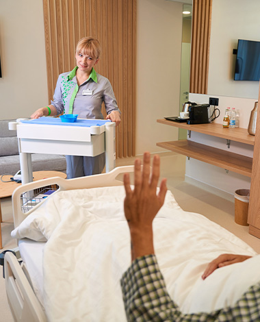 nurse attending to patient in modern hospital room with medical tray and friendly interaction promoting healthcare five essential elements