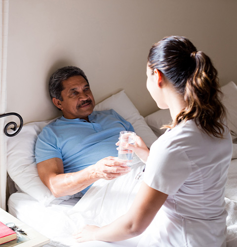 caregiver assisting patient with water in hospital room emotional support for elderly care