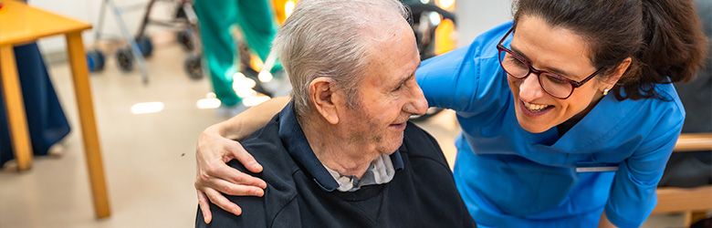 a caregiver smiling and interacting with an elderly man in a care facility promoting comfort and connection fostering joy for seniors