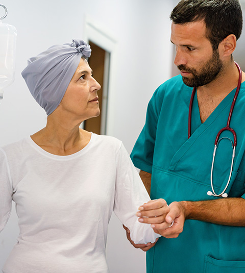 female cancer patient with headscarf receiving support from concerned male nurse in medical setting